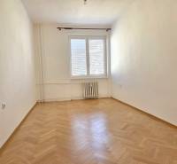 Üres szoba fa dekorációjú padlóval egy háromszobás lakásban, világos falak, radiátor.