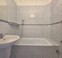 Fürdőszoba káddal egy háromszobás lakásban, világos kerámialapokkal burkolva.