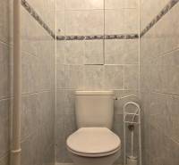 Fehér kerámia burkolatú WC egy háromszobás lakásban.