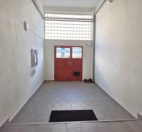 Folyosó csempével, amely a háromszobás lakás piros ajtajához vezet.