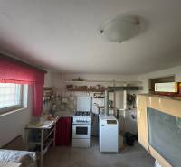 Családi ház konyhája régebbi tűzhellyel és élénkvörös függönyökkel.