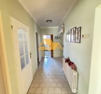 Családi ház folyosója csempézett padlóval és egyszerű dekorációval a falakon.