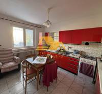 Konyha piros konyhabútorral egy családi házban, asztallal és székkel felszerelve.