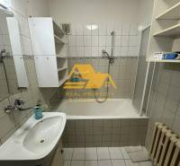 Fürdőszoba káddal, mosdóval, fehér szekrényekkel és radiátorral egy családi házban.