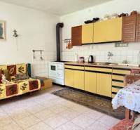 Családi ház konyhája bézs színű konyhaszekrényekkel és cserépkályhával.