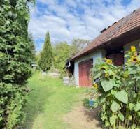 Családi ház Krivosúd-Bodovkán piros ajtókkal és napraforgókkal a kertben.