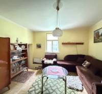 Nappali szőnyegekkel, könyvekkel, barna kanapéval és fa dekorációjú padlóval egy családi házban.