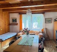 Izba egy családi házban fa gerendákkal, étkezőasztallal és két ággyal.