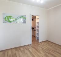 Szoba fa mintás padlóval és beépített szekrénnyel egy háromszobás lakásban.
