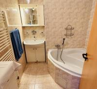 A háromszobás lakás fürdőszobája káddal, mosdóval és bézs csempékkel.