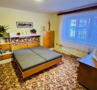 Szoba egy háromszobás lakásban fa dekorációjú bútorokkal és szőnyeggel a padlón.