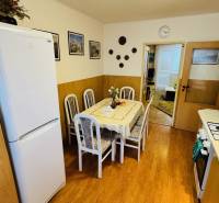 Konyha egy 3 szobás lakásban étkezőasztallal és fa dekorációjú padlóval.