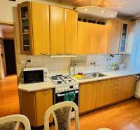 Konyha egy háromszobás lakásban, fa dekorációjú konyhapulttal és padlóval.