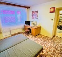 Szoba egy háromszobás lakásban szőnyeggel, íróasztallal és ággyal.