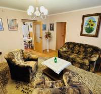 Nappali szoba fotelekkel, kanapéval és szőnyeggel egy háromszobás lakásban.