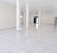 Tágas kereskedelmi helyiségek fehér padlóval és oszlopokkal, ideális vállalkozás számára.