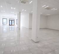 Tágas üzlethelyiségek fehér falakkal és fényes padlóval.