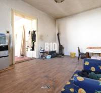 Szoba egy családi házban fa dekor padlóval, kályhával és virágmintás szövettel borított bútorokkal.