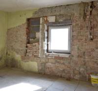 Szoba egy családi házban téglafalakkal és egy vödörrel a padlón.