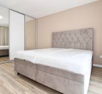 Hálószoba egy háromszobás lakásban kényelmes ággyal, beépített szekrénnyel és fa dekorációjú padlóval.