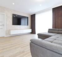 Nappali egy háromszobás lakásban kanapéval és fa dekorációjú padlóval.