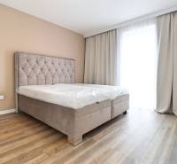 Hálószoba ággyal és fa dekorációjú padlóval egy háromszobás lakásban.