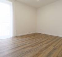 Szoba egy háromszobás lakásban, fa dekorációjú padlóval és egyszerű dizájnnal.