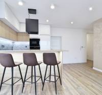 Konyha bárpulttal és fa dekorációjú padlóval egy háromszobás lakásban.