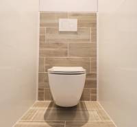 Fa dekorral és fehér csempékkel ellátott WC egy háromszobás lakásban.