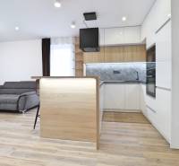 Nappali konyhával és fa dekoros padlóval egy háromszobás lakásban.