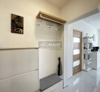 1 szobás lakás belső tere fogassal, cipősszekrénnyel és polcokkal az ajtó mellett.