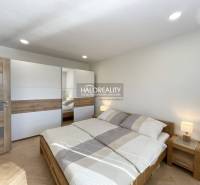 Hálószoba fa mintázatú padlóval egy egyszobás lakásban, világos ágy és szekrény.