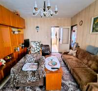 Nappali egy háromszobás lakásban fa dekorációval, szőnyeggel és kanapékkal.