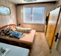 Hálószoba egy háromszobás lakásban ággyal, szekrénnyel és fa dekorációjú padlóval.