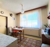 Ebédlő egyszerű bútorokkal egy háromszobás lakásban, padló dekoratív szőnyeggel.