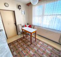 Konyha egy háromszobás lakásban étkezőasztallal, székekkel és szőnyeggel.