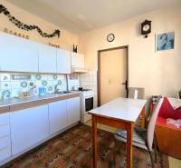 Konyha egy háromszobás lakásban fehér szekrényekkel és dekoratív csempékkel.