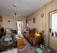 Nappali egy háromszobás lakásban, fotelekkel, virágokkal és vintage csillárral.