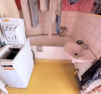 Fürdőszoba mosdóval, káddal és mosógéppel egy háromszobás lakásban.