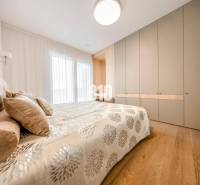 Hálószoba egy háromszobás lakásban ággyal, beépített szekrénnyel és fa dekorációjú padlóval.