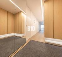 Folyosó egy 3 szobás lakásban fa mintázatú padlóval és tükörrel.