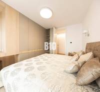 Hálószoba egy háromszobás lakásban tárolóhelyekkel és mintás textíliákkal ellátott ággyal.