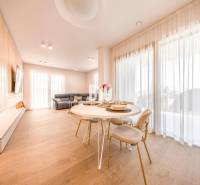 Nappali egy háromszobás lakásban, fa dekorációjú padlóval, étkezőasztallal és kanapéval.