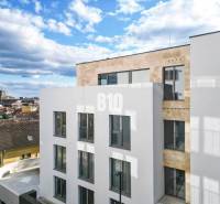 Fehér épület nagy ablakokkal Pozsony III-ban, a Matúškova utcában, háromszobás lakással.