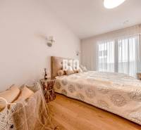 Hálószoba egy háromszobás lakásban, fa mintázatú padlóval és ággyal.