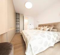 Világos hálószoba fa hatású padlóval és beépített szekrényekkel egy háromszobás lakásban.