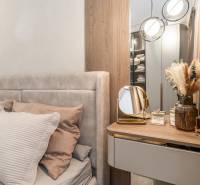 Hálószoba egy háromszobás lakásban ággyal, tükörrel és dekoratív elemekkel.