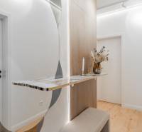 Folyosó egy 3 szobás lakásban minimalista asztallal, tükörrel és fa dekoros padlóval.