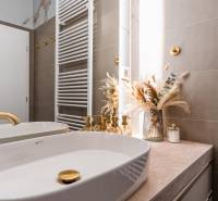 Fürdőszoba arany részletekkel és dekorációval egy háromszobás lakásban.