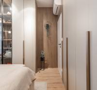 Hangulatos hálószoba fa dekor padlóval és üvegszekrénnyel egy háromszobás lakásban.